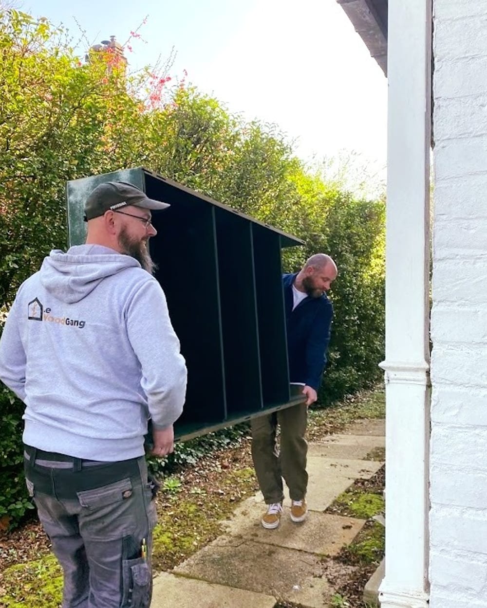 Deux membres du Wood Gang portent un élément de la bibliothèque jusqu'à la maison