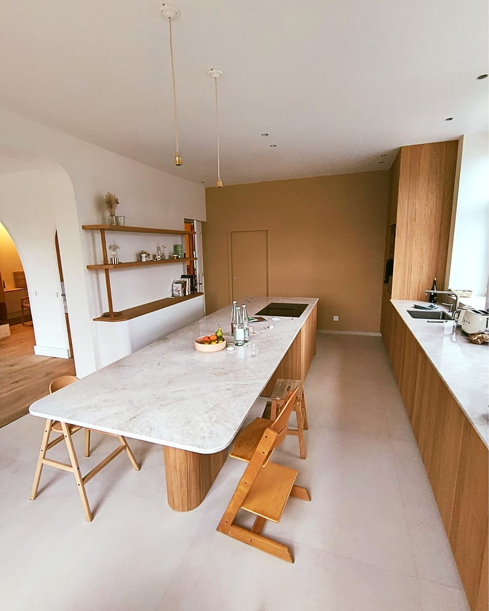 Long îlot arrondi en chêne avec plan de travail en pierre et coin repas, par Le Wood Gang