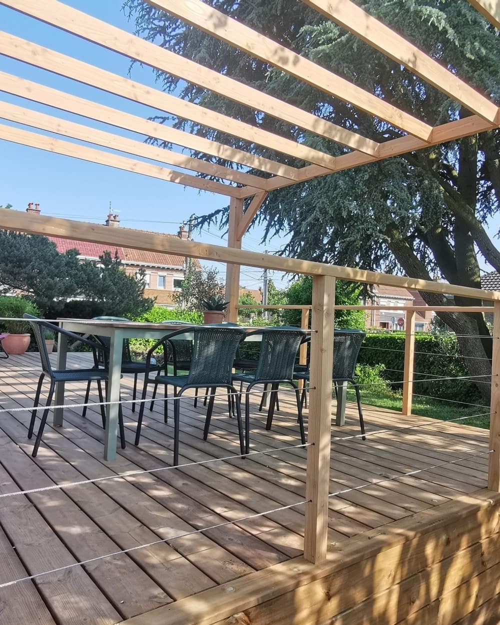 Sous la pergola en douglas, la table et les chaises sur la terrasse en bois
