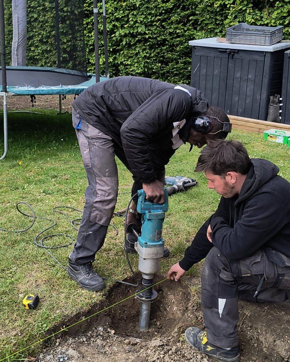 Deux membres du Wood Gang vissent une vis de fondation dans le jardin
